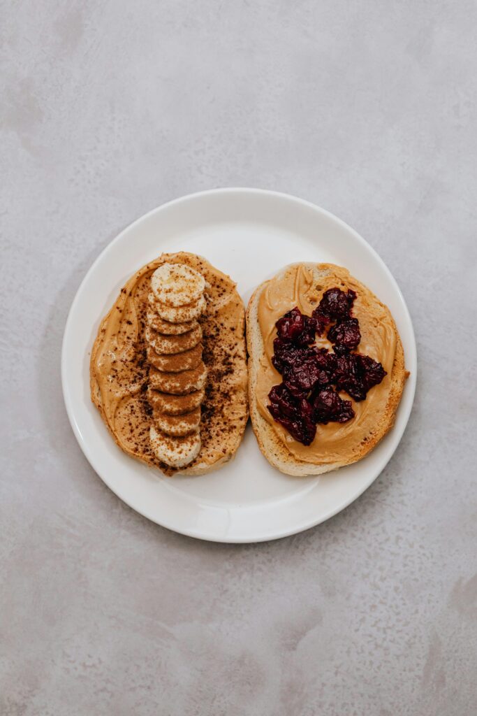 Delicious peanut butter toast topped with banana slices and berry jam, perfect for a healthy snack.