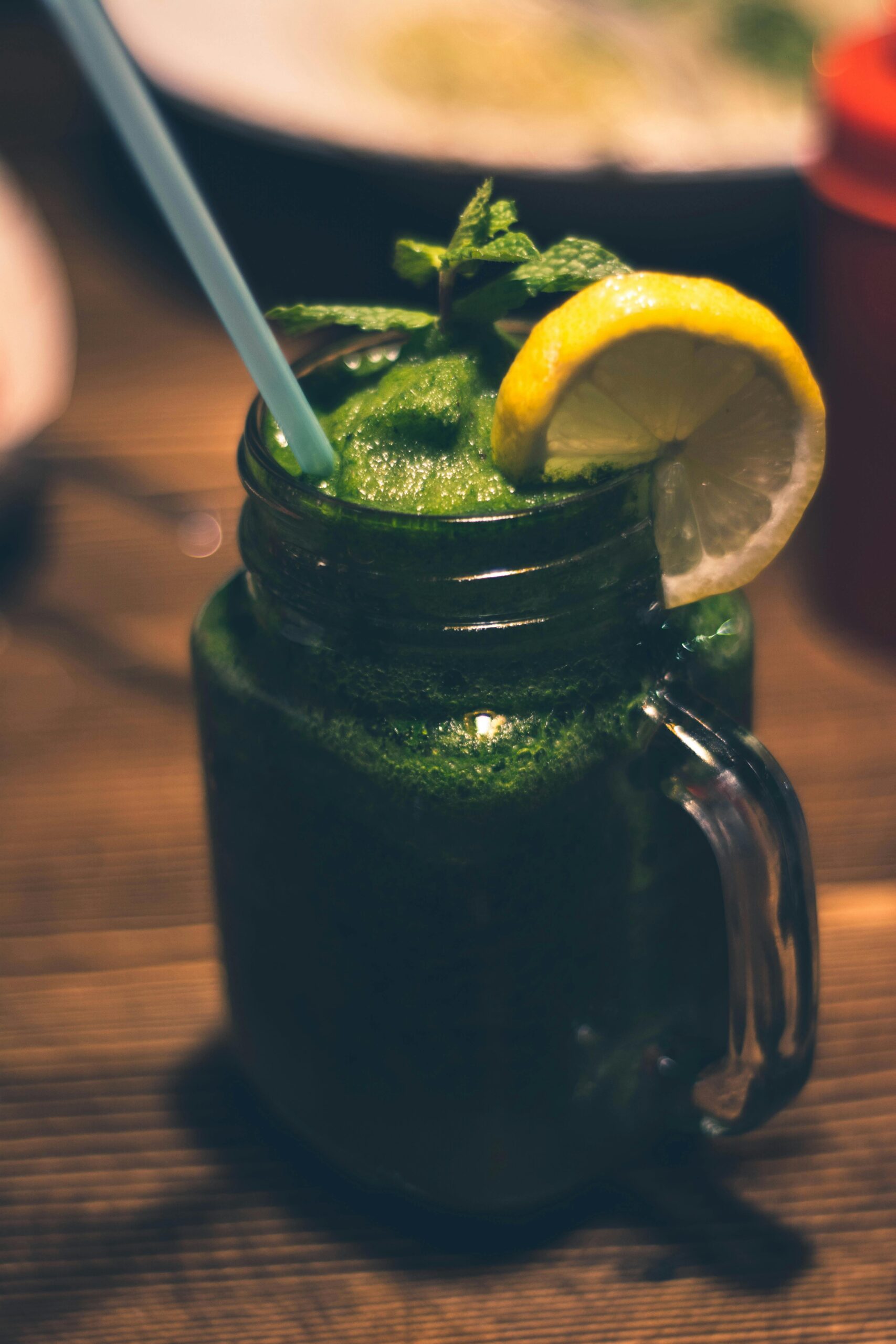 A delicious green smoothie in a mason jar with a lemon slice and mint garnish, perfect for a healthy refreshment.